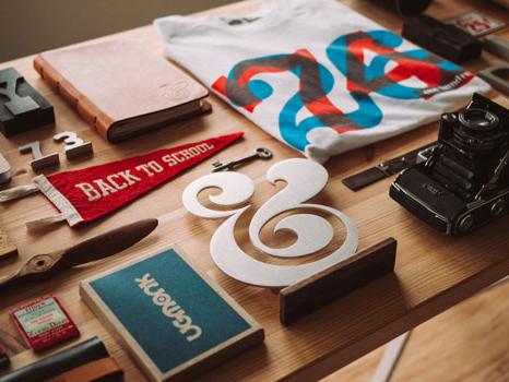 Printed brand materials, badges and stationery laid out on a desk