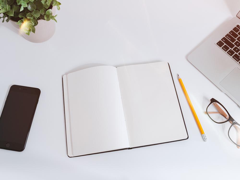 Marketing plan notebook, phone and laptop on a clean desk